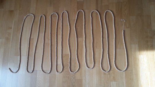 Leere Tausenderkette (Kette bestehend aus 1000 Perlen) in Schlangenlinien angeordnet.