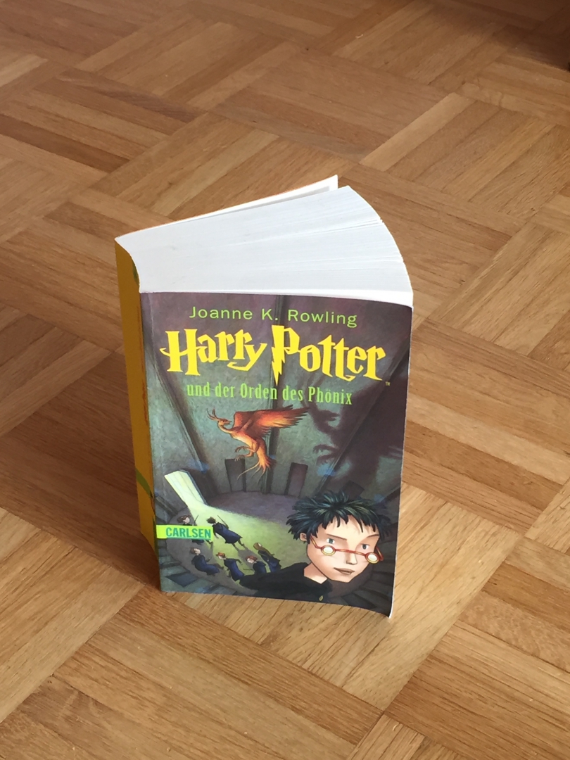 Foto eines Buchs, welches auf dem Boden steht. Titel: „Harry Potter und der Orden des Phoenix“.