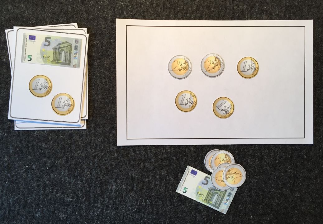 Links Stapel mit Karten auf denen Geldbeträge mit Scheinen und Münzen dargestellt sind, z.B. Fünfeuroschein und 2 Eineuromünzen. Rechts daneben Sortiertafel, darauf 2 Zweieuromünzen und 3 Eineurostücke. Darunter weitere Geldscheine und -münzen.