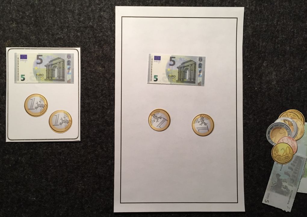 Links: Karte mit einem Fünfeuroschein und 2 Eineuromünzen darauf. Rechts: Sortiertafel mit einem Fünfeuroschein und 2 Eineuromünzen darauf. Rechts daneben weitere Geldscheine und -münzen.