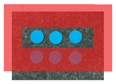 2 mal 3 Punktefeld (blaue Plättchen auf schwarzem Untergrund). Eine transparente rote Folie liegt über dem Punktebild, ein ausgeschnittenes Sichtfenster zeigt die erste Reihe. 